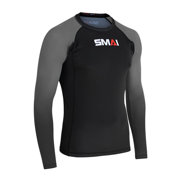 The SMAI Long Sleeve Rash Guard - Grey features a black torso, dark grey sleeves, and the SMAI logo in white and red on the chest. With its fitted design, it's ideal for no-gi grappling or MMA training sessions.