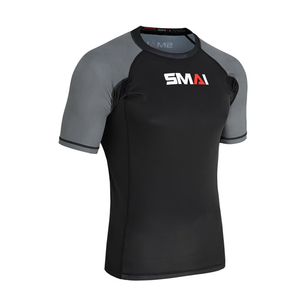 The SMAI Short Sleeve Rash Guard - Grey features black front and back panels, gray sleeves, and a white/red "SMAI" chest logo. This fitted compression shirt is perfect for MMA or no-gi BJJ training sessions.