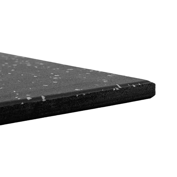 Close-up of the corner of an SMAI Rubber Gym Flooring Tile - 15mm - Grey Fleck, featuring small grey specks on a black surface and shown against a white background. The tile appears thick and robust, designed for use as gym flooring or other protective surfaces, offering excellent durability and non-slip properties.