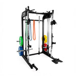The SMAI All-In-One Home Gym Trainer - Plate Loaded (Demo Stock) is a black and silver squat rack with weight plates, resistance bands, pull-up bars, and cable attachments—all set against a plain white background.