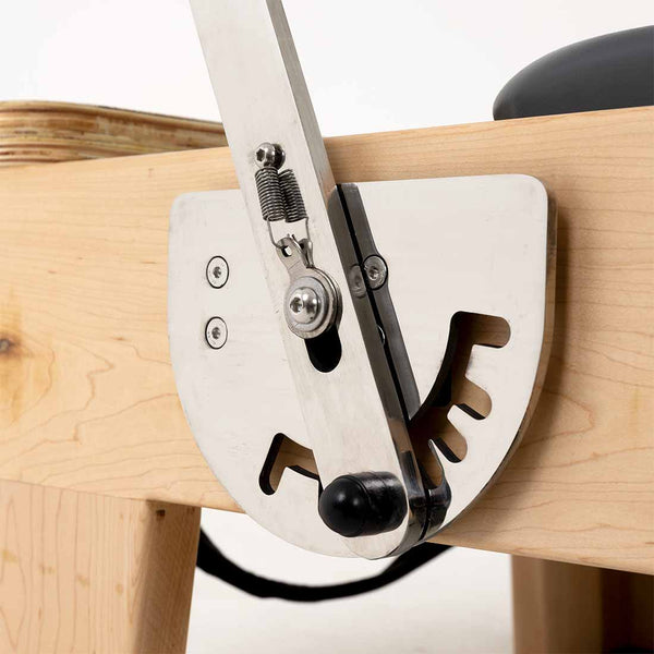 Close-up of a metal lever with a spring and adjustment notches on the SMAI Pilates - Classical Maple Reformer, showing its adjustable features.