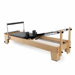 The SMAI Pilates - Classical Maple Reformer features a padded platform, adjustable foot bar, shoulder rests, and black resistance cords—ideal versatile Pilates equipment for a range of workouts.