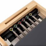 Close-up of the SMAI Pilates - Classical Maple Reformer, featuring five metal resistance springs on color-coded knobs and a black padded surface. This adjustable equipment has a sturdy maple wooden frame for versatile workouts.