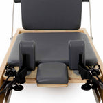 Close-up of the SMAI Pilates - Classical Maple Reformer, showcasing padded gray cushions, adjustable straps, and a maple wood frame—ideal adjustable equipment for pilates exercise and fitness routines.