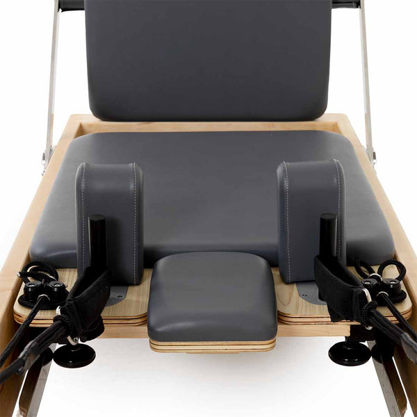 Close-up of the SMAI Pilates - Classical Maple Reformer, showcasing padded gray cushions, adjustable straps, and a maple wood frame—ideal adjustable equipment for pilates exercise and fitness routines.