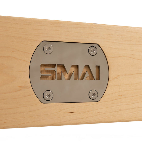 A close-up of the SMAI metal plate, fixed with four screws on the light maple surface of the Pilates - Classical Maple Reformer, showcases its commercial-grade quality for professional pilates studios.