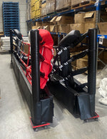 The 5m Boxing Ring - Floor Mount Folding by SMAI is stored upright on wheeled platforms with its red and black padding visible. It is surrounded by boxes and shelving units filled with various items, located in a warehouse setting where the ring components are floor-mounted.