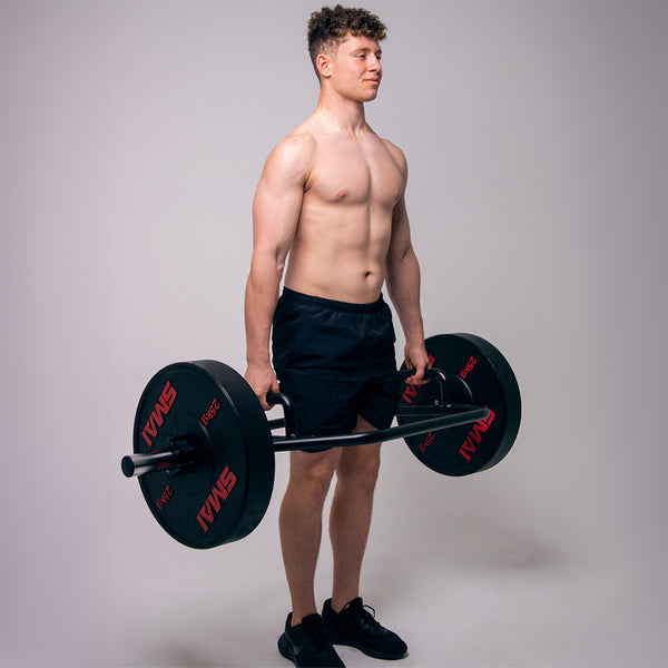 Man standing holding compact trap bar and 25kg HD Bumper SMAI Plates