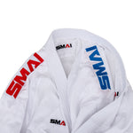 Close-up of a white WKF Reversible Karate Uniform - 6oz Premium Kumite Gi - Inazuma RX, featuring red and blue SMAI logos on the collar and sleeves. The fabric appears textured and neatly folded, designed for excellence in martial arts competitions.