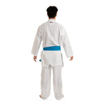 A person in a white WKF Reversible Karate Uniform by SMAI, featuring the 6oz Premium Kumite Gi of the Inazuma RX series and a blue belt, stands facing away against a white background to showcase the reversible jacket.
