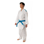 Wearing a SMAI WKF Reversible Karate Uniform – 6oz Premium Kumite Gi, Inazuma RX, a person with a blue belt stands barefoot, facing slightly to the right against a simple white background that highlights the gi's design and stance.