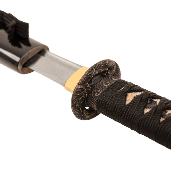 Close-up of the SMAI Damascus Black Infinite Dragon Tanto, featuring a Damascus-folded steel blade, partially unsheathed to show an intricate dragon-themed tsuba and a handle wrapped in black cord.