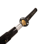 A detailed view of the SMAI Katana - High Carbon Black, partially unsheathed to display its shiny clay-tempered hamon blade, ornate round guard, and black-wrapped handle.