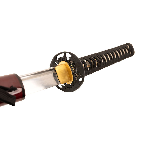 A close-up of the SMAI Katana - Damascus Maroon, partially drawn from its scabbard to reveal the sharp steel blade, ornate handguard, and black diamond-patterned handle wrapping.