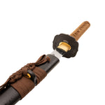 A close-up shows the SMAI Forged Katana - Black Copper Dragon, partially drawn from its black sheath, featuring a brown-wrapped handle, ornate guard, and a glimpse of the polished blade.