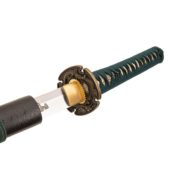 A close-up of the SMAI Katana - Emerald Dragon partially unsheathed, highlighting its brass guard, green diamond-pattern handle wrap, clay-forged Hamon blade detail, and a contrasting black sheath.