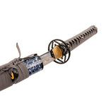 A close-up of the SMAI Medium Carbon Blue Katana - Dark Atlantis, a full tang katana with a black and gold handguard, gray-wrapped handle, patterned blue and white scabbard, and its medium carbon steel blade partially drawn.
