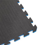 A close-up of SMAI Jigsaw Mat - 2cm - Factory Seconds shows black mats with blue edges, textured surfaces, and puzzle-like connectors. Cosmetic imperfections are visible due to factory seconds quality.