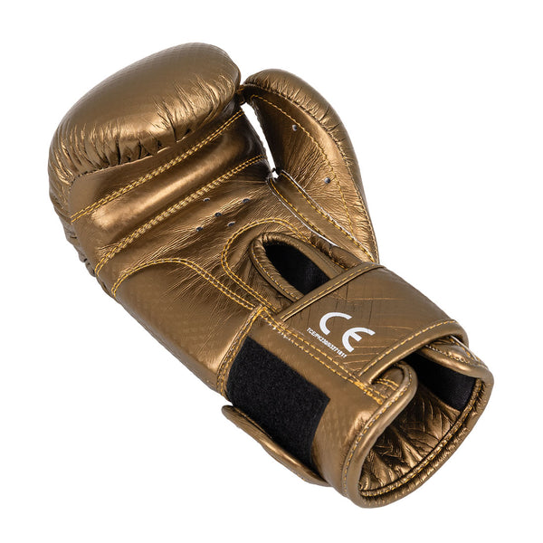 A single SMAI Essentials Kids Boxing Glove in gold with black Velcro straps and visible stitching rests on a white background, featuring a CE marking on the wrist strap.