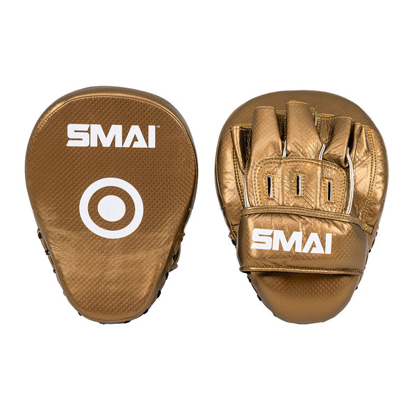 A pair of SMAI Essentials Boxing Mitts in gold, featuring the brand name in white. One mitt has a white target circle; the other shows finger and wrist slots.