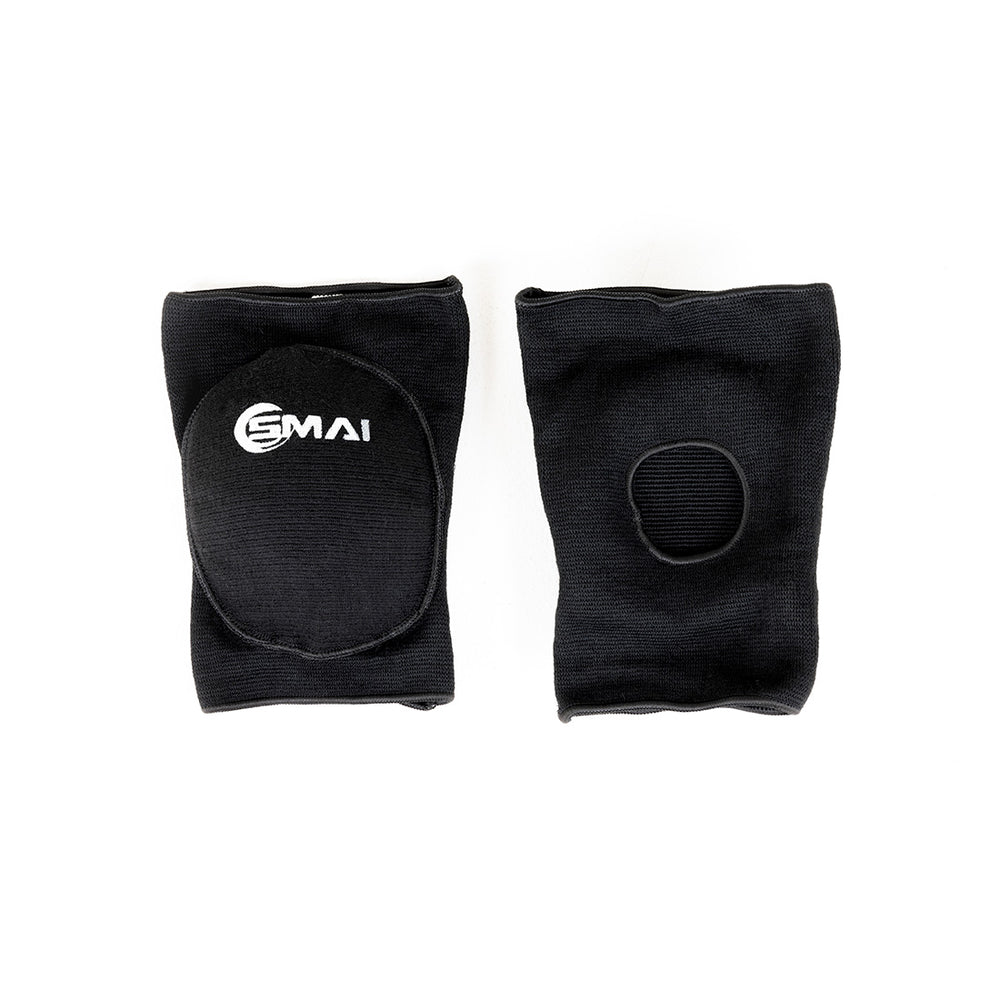Two black SMAI Padded Knee Guards (Extra Small) are shown flat on a white background. One displays the SMAI logo and padded oval front; the other shows a circular opening at the back, ideal for judo and martial arts.