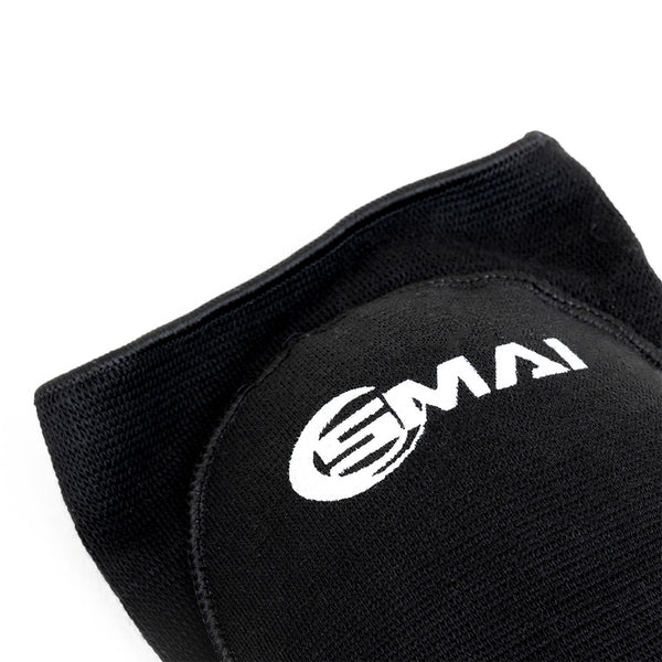 Close-up of the SMAI Padded Knee Guard - Extra Small in black, featuring a white logo, textured surface, and detailed stitching—ideal for judo and martial arts.