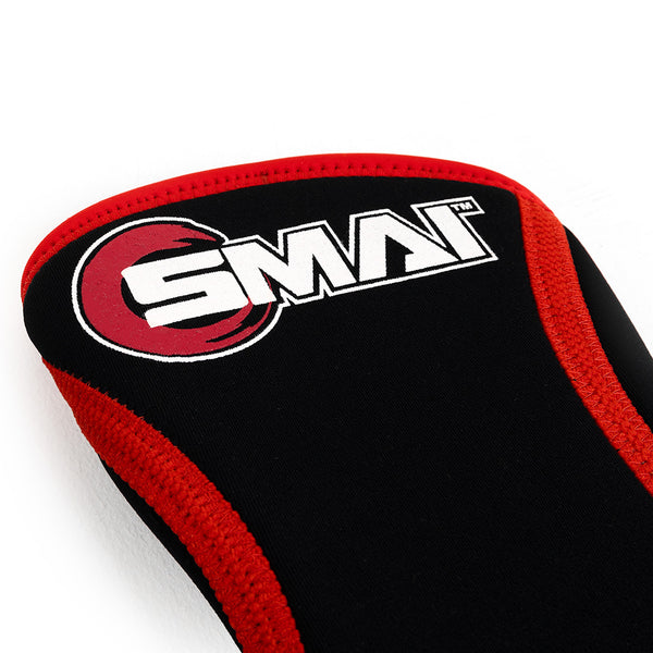 An image features a black neoprene sports knee sleeve with red trim and an ergonomic curve. "SMAI" is boldly displayed in white next to a red circle design, set against a plain white background.