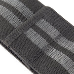 Close-up of a textured, dark gray band from the Knitted Mini Resistance Bands set by No Sync To Channel Engine, featuring two parallel lighter gray woven lines along its length. A rectangular fabric loop is secured across the strap for added detail, making it perfect for enhancing your workout with effective glute activation exercises.