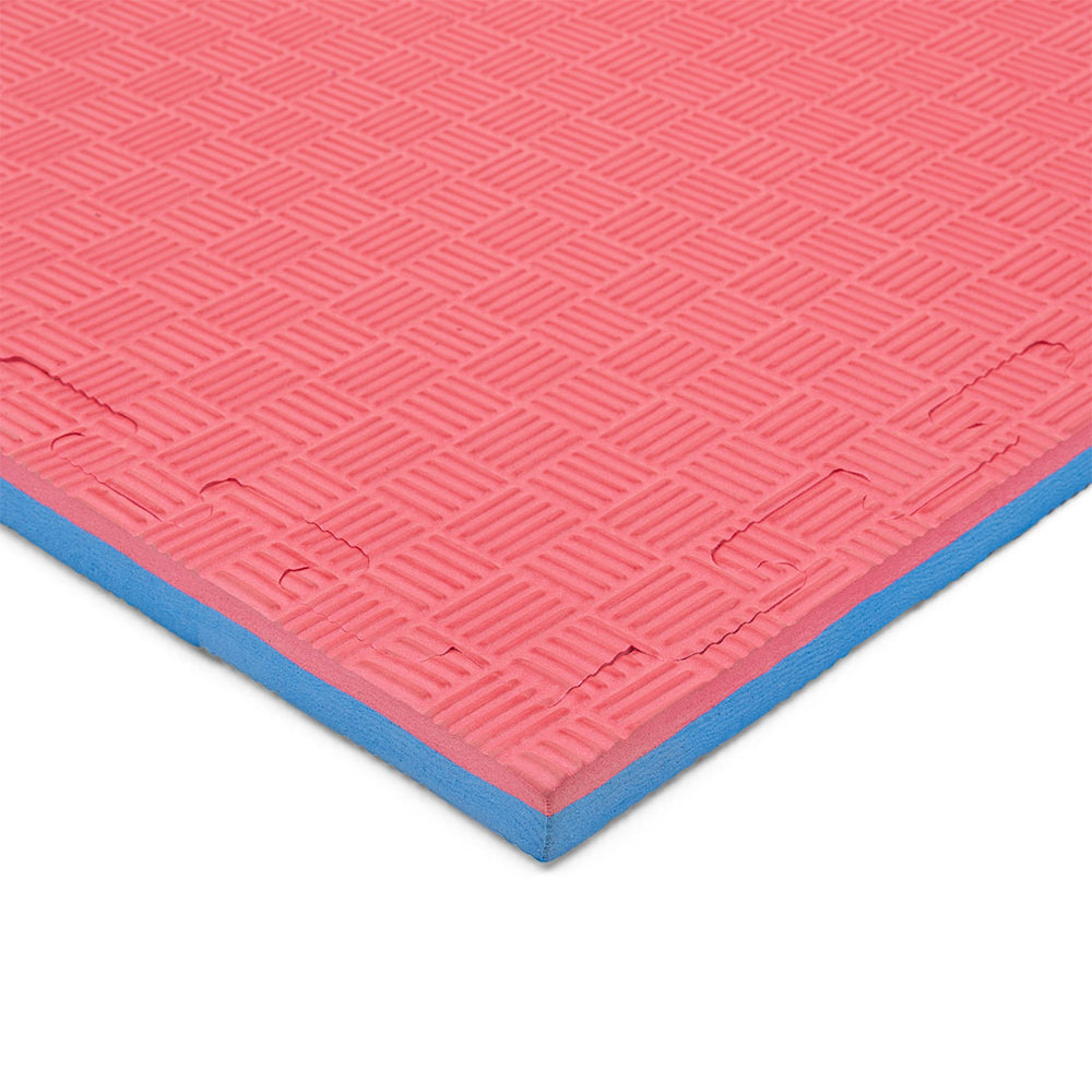 A close-up of the SMAI Jigsaw Mat - 2cm Korean Style - Factory Seconds, showing its pink textured grid surface with blue underside and cosmetic imperfections, viewed from an angle.