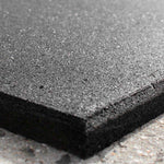 Close-up of the SMAI Rubber Gym Flooring Tile - 15mm - Black, featuring a textured, shock-absorbent surface with a slightly rough and grainy appearance. The tile is displayed on a contrasting light-colored background, reminiscent of an acoustic panel.