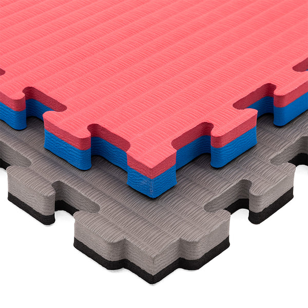 Three SMAI Jigsaw EVA Mats (Value Range, 3cm) are stacked: red/blue on top, blue/gray in the middle, and gray/black at the bottom. These mats have a textured EVA foam surface ideal for martial arts flooring.