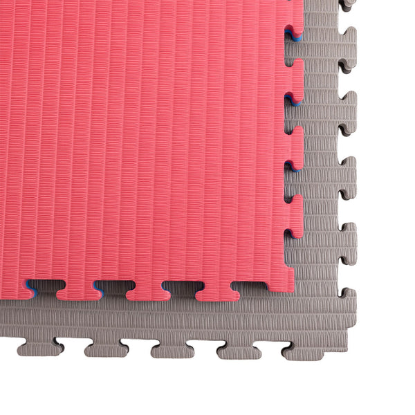 Close-up of SMAI Jigsaw EVA Mat - Value Range - 4cm, showing a red mat partially covering a gray one. The textured surface and interlocking edges make these mats perfect for seamless gym flooring.