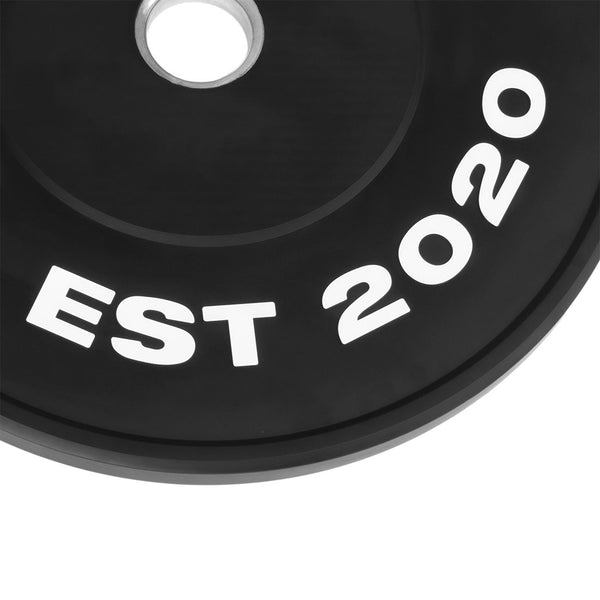 Close-up of a black SMAI The Yard - HD Bumper Plate (25kg), featuring bold white "EST 2020" text curved along the edge—ideal for home gym use.