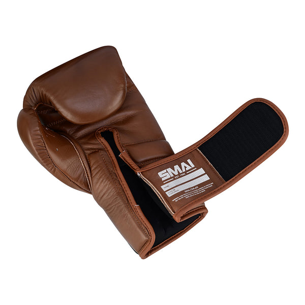 The SMAI Memory Tec Leather Boxing Glove - Antique Brown is shown with its wrist strap open, revealing the inner lining and Memory Tech foam padding. The glove features a black and white SMAI label.