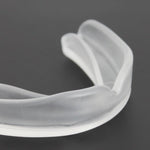 Close-up image of a transparent SMAI Mouthguard on a dark surface, alongside its sleek clear storage case.