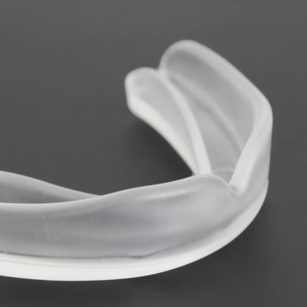 Close-up image of a transparent SMAI Mouthguard on a dark surface, alongside its sleek clear storage case.