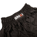 Close-up of the waistband of SMAI Muay Thai Shorts - Black, featuring a gathered elastic band and a sewn-on SMAI label in white and red letters.