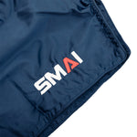 Close-up of Muay Thai Shorts - Navy by SMAI, made from satin polyester, featuring "SMAI" embroidered in white with a red "A" on the neatly stitched edge.