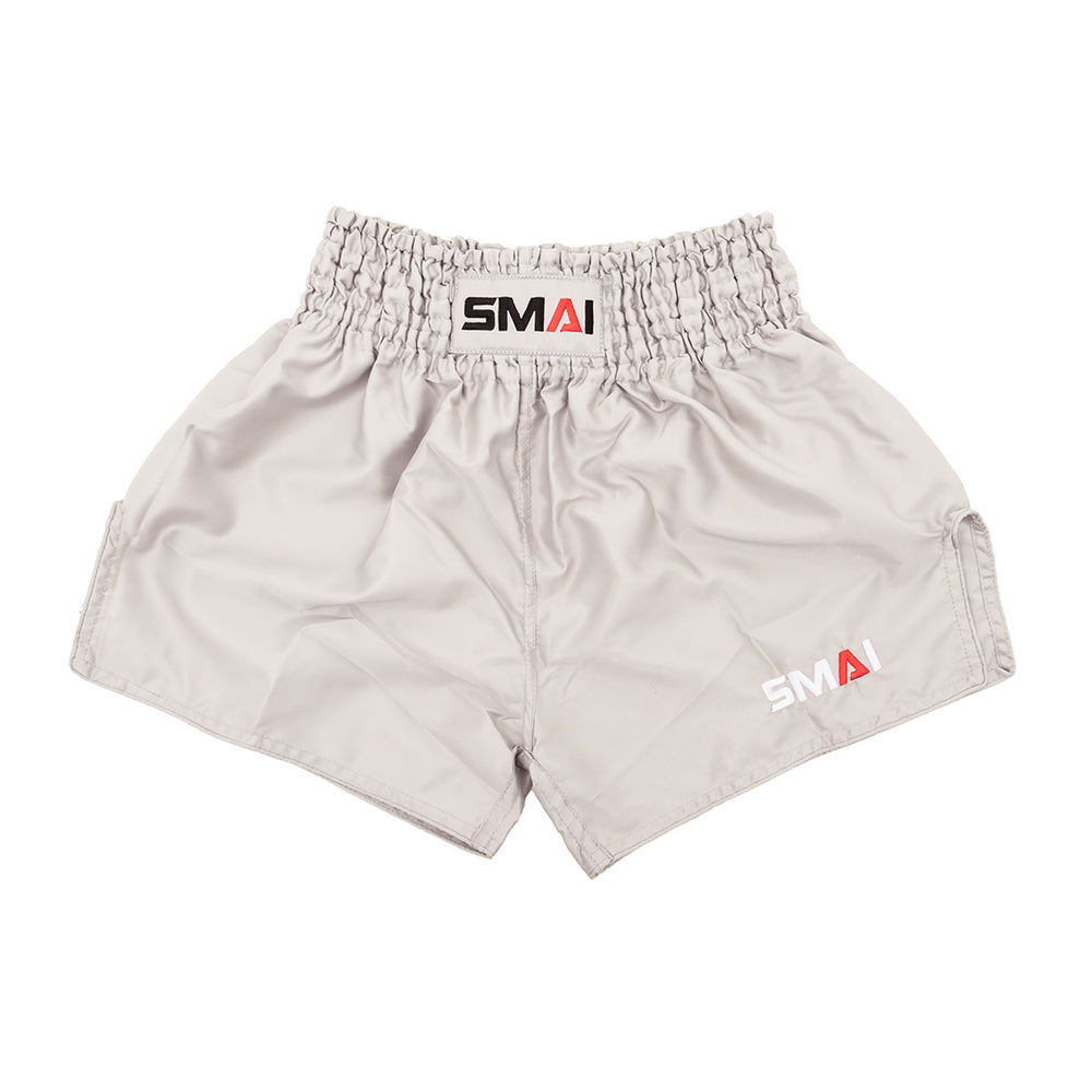 SMAI Muay Thai Shorts - Grey: unisex, slightly shiny satin polyester with a high elastic waistband and black, red, and white SMAI logo on the waistband and lower left leg.