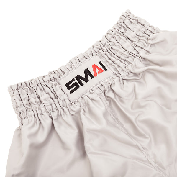 Close-up of the elastic waistband on SMAI’s Muay Thai Shorts - Grey, featuring a sewn-on white patch with the brand name "SMAI" in black and red letters.