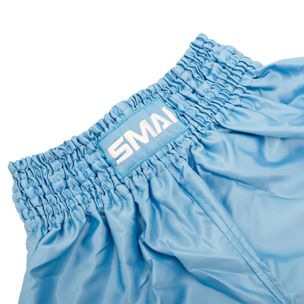 SMAI Muay Thai Shorts - Sky Blue: Unisex satin polyester shorts with a wide ruched elastic waistband. Features a rectangular white and blue "SMAI" label on the front center of the waistband.