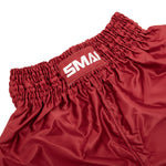 Close-up of the waistband on SMAI’s Muay Thai Shorts - Red, showing shiny, quick-dry satin fabric, a gathered elastic band, and a rectangular patch with partially visible white "SMAI" text.