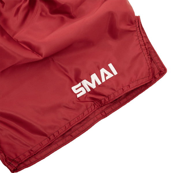 SMAI Muay Thai Shorts - Red: Unisex shorts with a white "SMAI" logo on the bottom hem, made from smooth, quick-dry satin with a slightly wrinkled look.