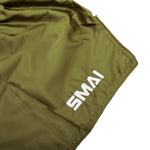 A close-up of SMAI’s Muay Thai Shorts in olive green Satin Polyester, showcasing the white "SMAI" embroidery in the corner and the slightly wrinkled unisex fabric.