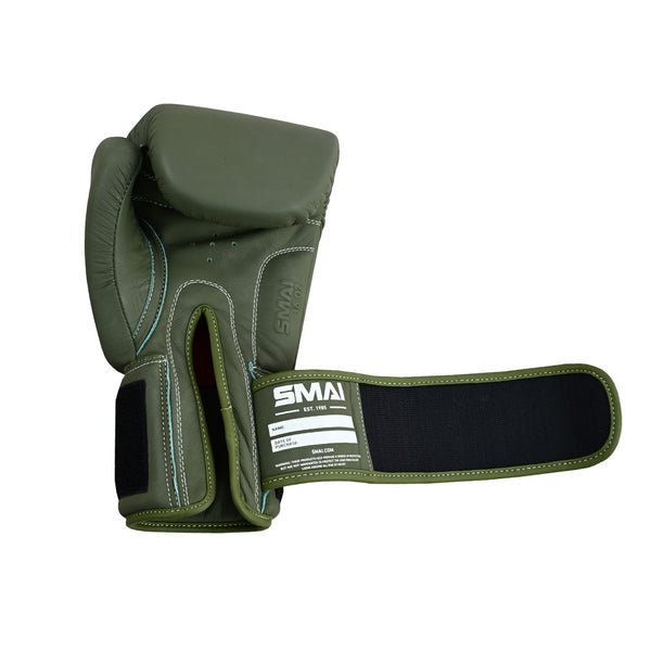 The SMAI Elite85 Boxing Glove in olive green features leather construction, a large Velcro wrist strap for injury reduction, white stitching, and the "SMAI" label. The injection-moulded glove is open to reveal the interior and extended wrist support.