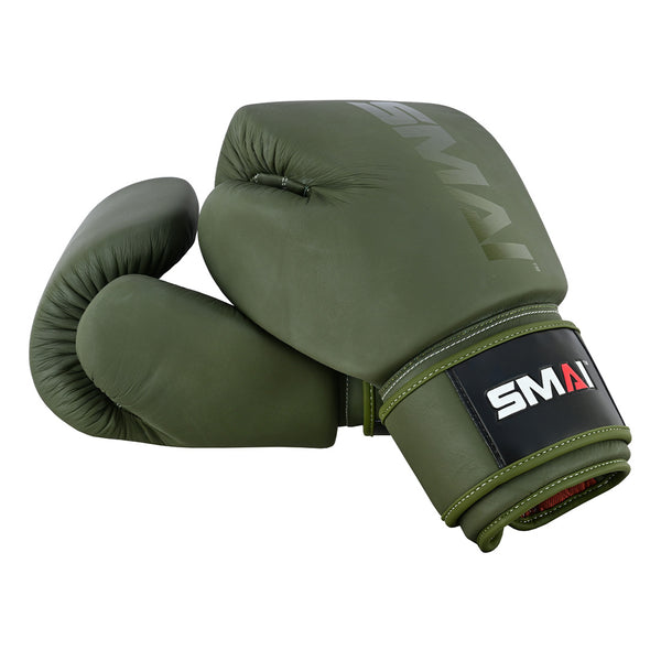 The SMAI Elite85 Boxing Glove in olive green features injection-moulded leather, a black wrist strap, and the SMAI logo in white, red, and grey. One glove lies flat while the other stands upright.