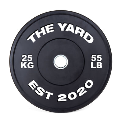 The SMAI The Yard - HD Bumper Plates (Pair) - 25kg are black plates made from high-density virgin rubber with white "THE YARD" branding, "25 KG," "55 LB," and "EST 2020" text. Ideal for home gyms, they feature a central mounting hole.