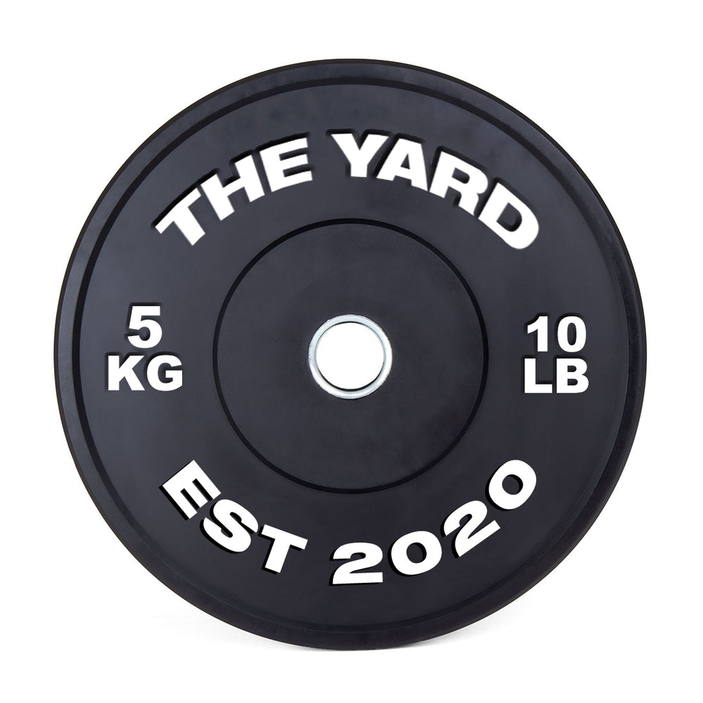 The SMAI The Yard - HD Bumper Plate (Pair) 5kg features a black design with "THE YARD" at the top, "5 KG" left, "10 LB" right, and "EST 2020" below, plus a silver center—ideal for Olympic or CrossFit training.