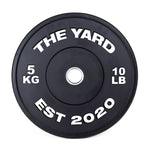 The SMAI The Yard - HD Bumper Plate (Pair) 5kg features a black design with "THE YARD" at the top, "5 KG" left, "10 LB" right, and "EST 2020" below, plus a silver center—ideal for Olympic or CrossFit training.
