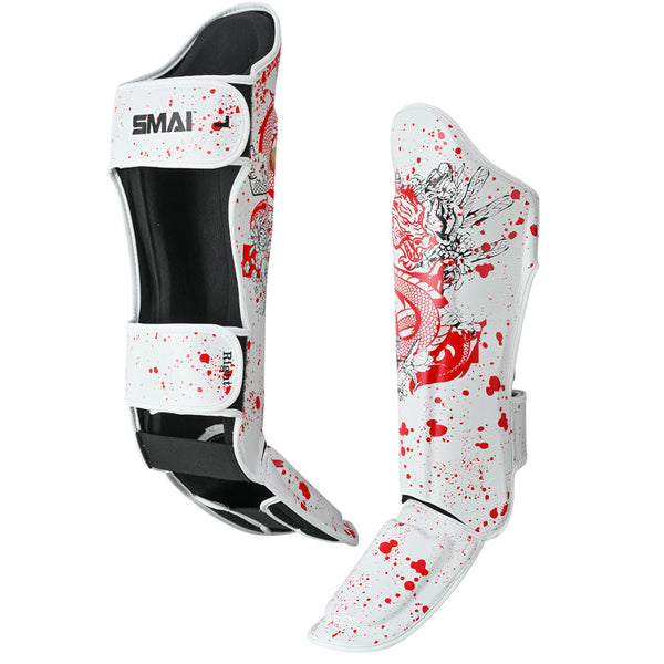 Two SMAI Muay Thai Shin Instep Guards - White Dragon are shown: one front, one side view. These white guards feature red dragon and splatter designs, black interior padding, adjustable straps, and durable EVA foam for comfort and safety.